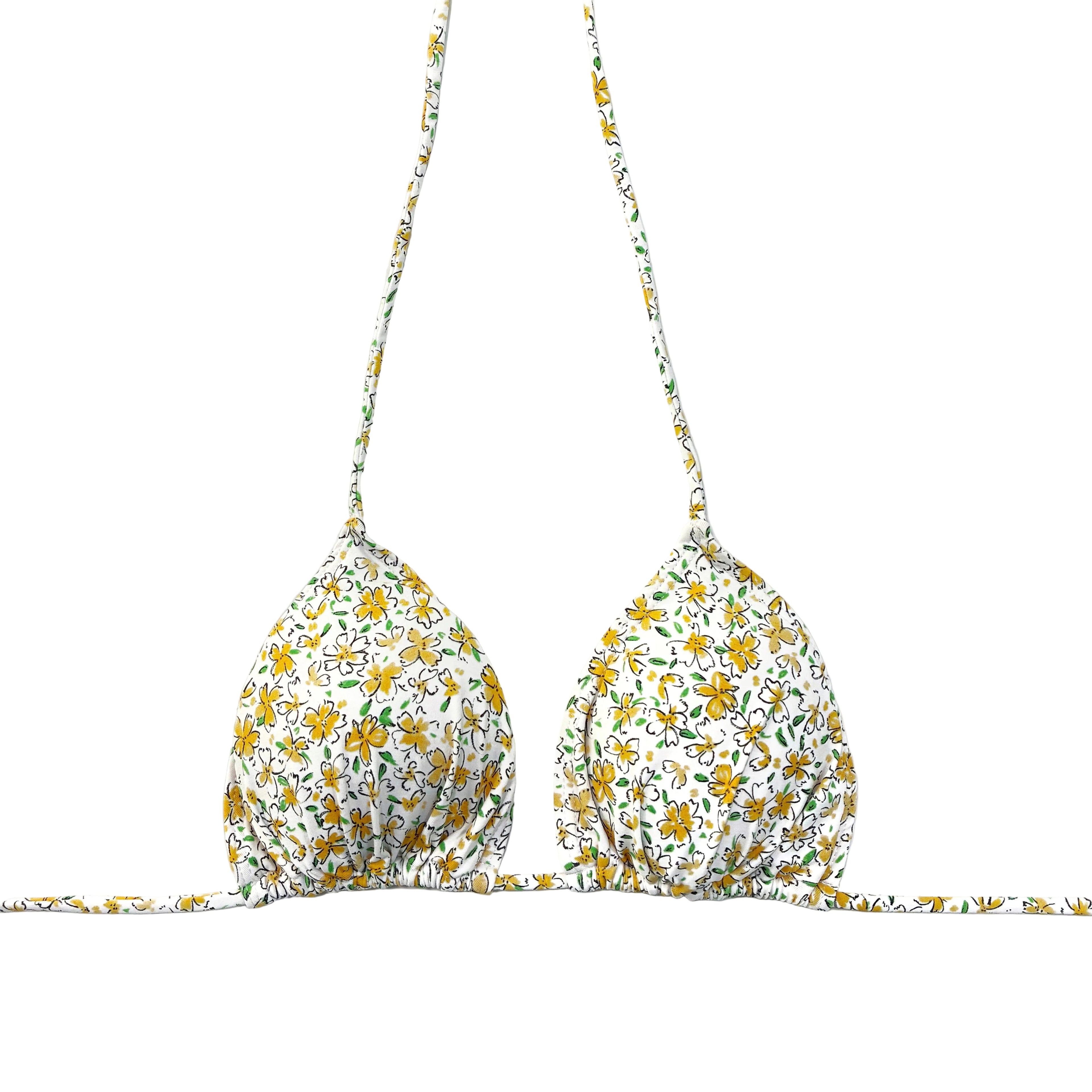 Bikini artesanal de triángulo cortina con estampado de flores amarillas sobre fondo blanco en la playa.