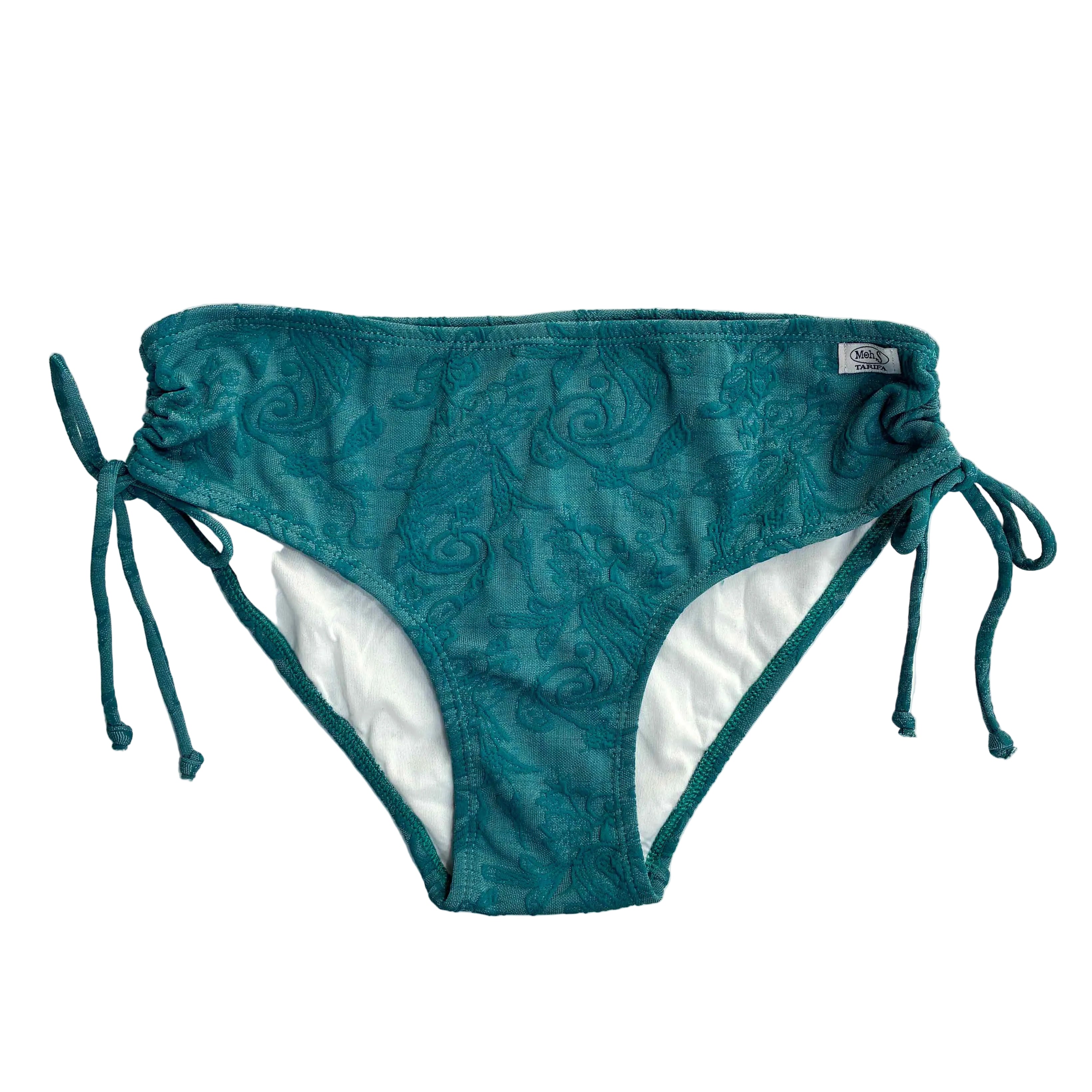 Primer plano de la braguita de bikini ajustable de tiro medio 'Mala Tarifa' en color turquesa con textura damascada. Cuenta con lazos laterales y etiqueta de marca. Fondo blanco.
