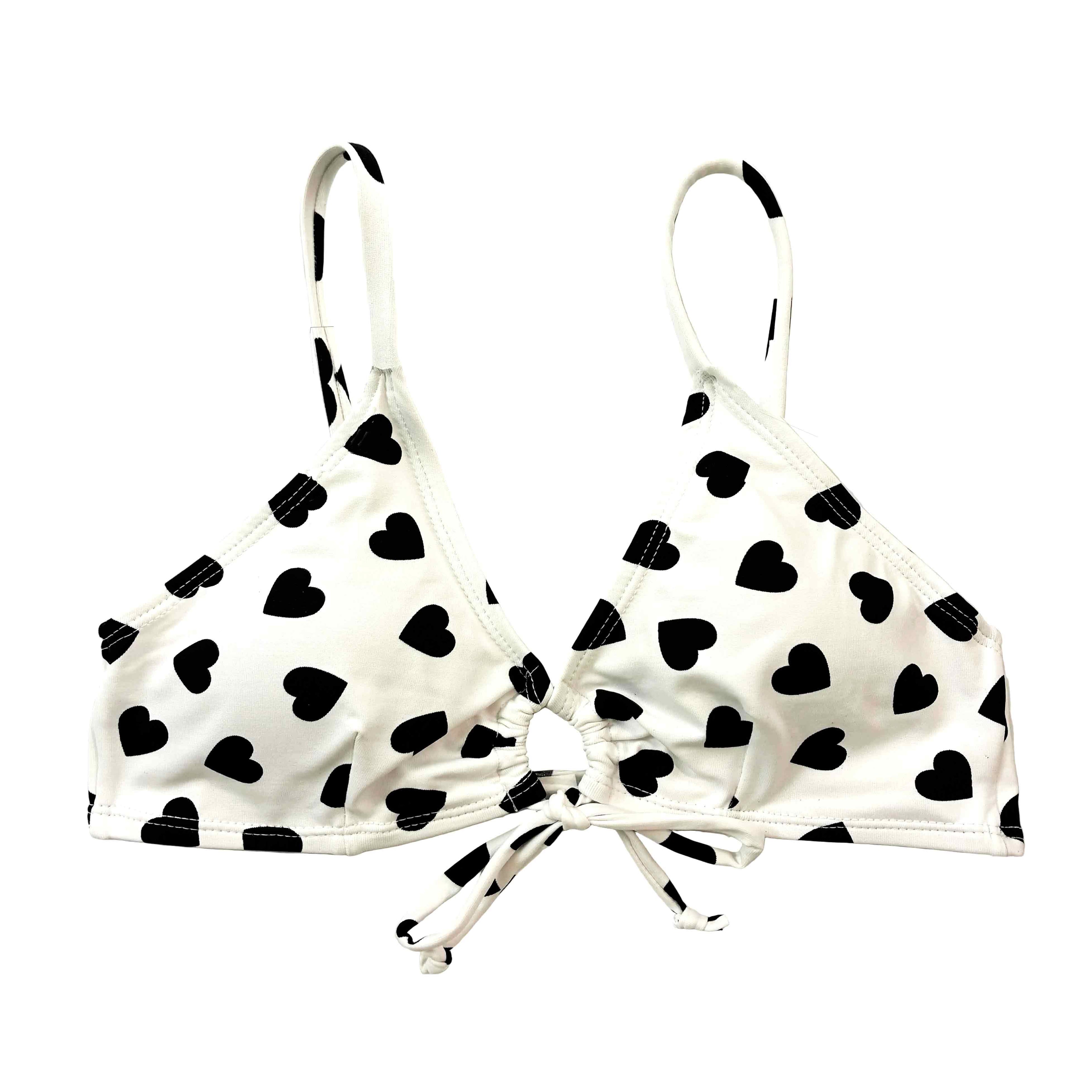 Bralette de bikini blanco con estampado de corazones negros, diseño artesanal con nudo central y tirantes finos regulables.