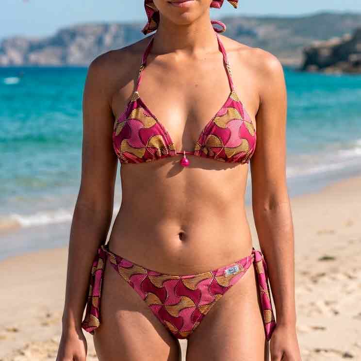 Chica con top de bikini artesanal en forma de triángulo con estampado geométrico tribal en tonos rojos, ocres y amarillos.