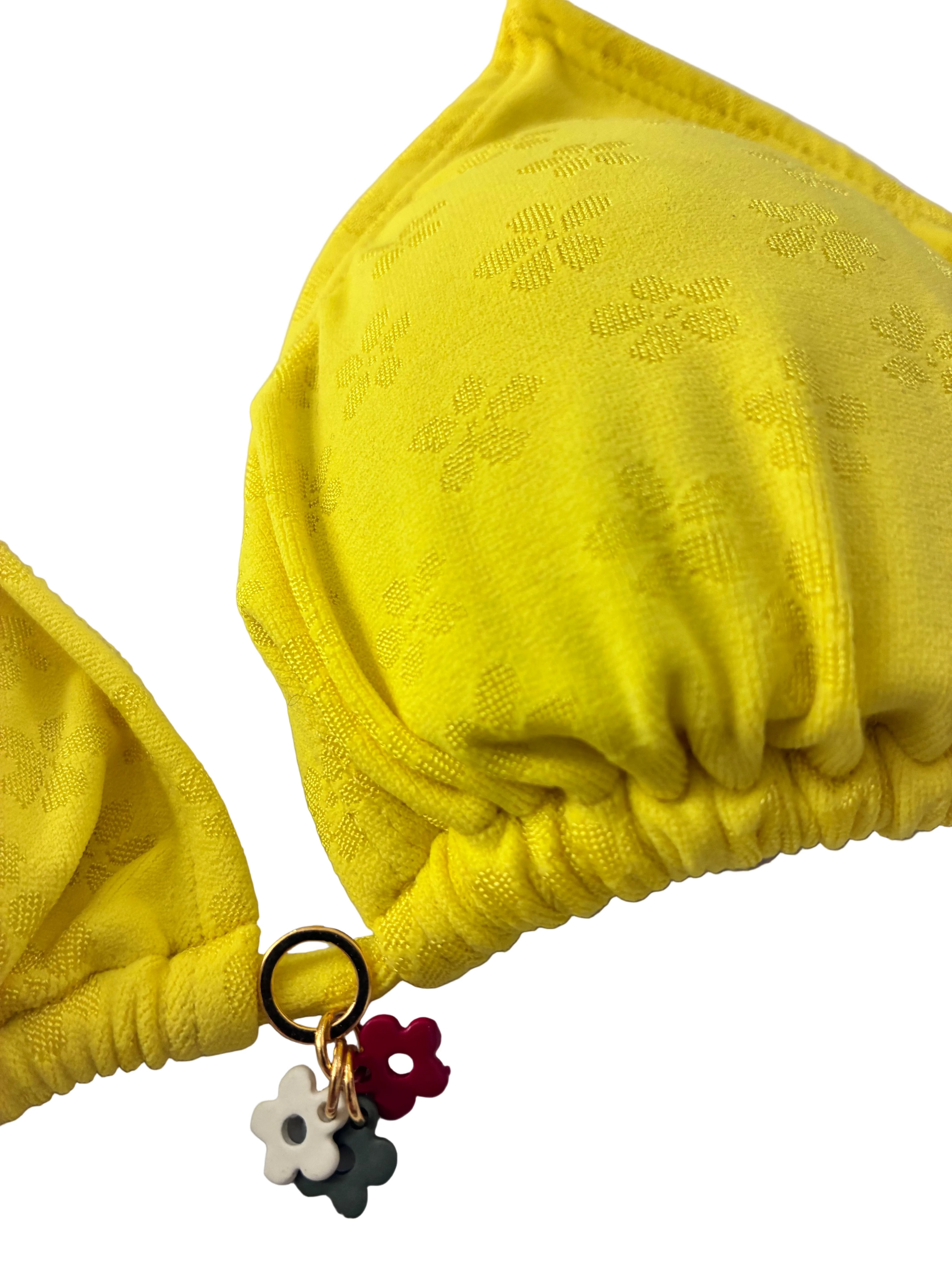 Detalle de adorno floral de top de bikini amarillo intenso con lycra texturada en flores