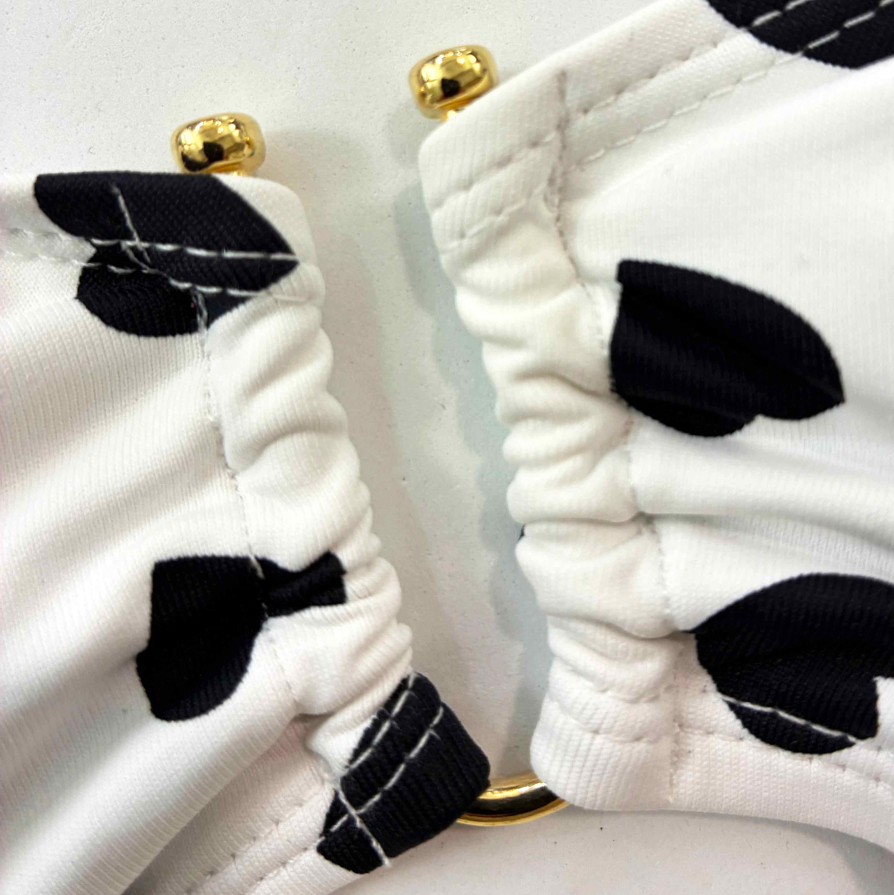 Detalle dorado de bikini blanco de corazones negros.